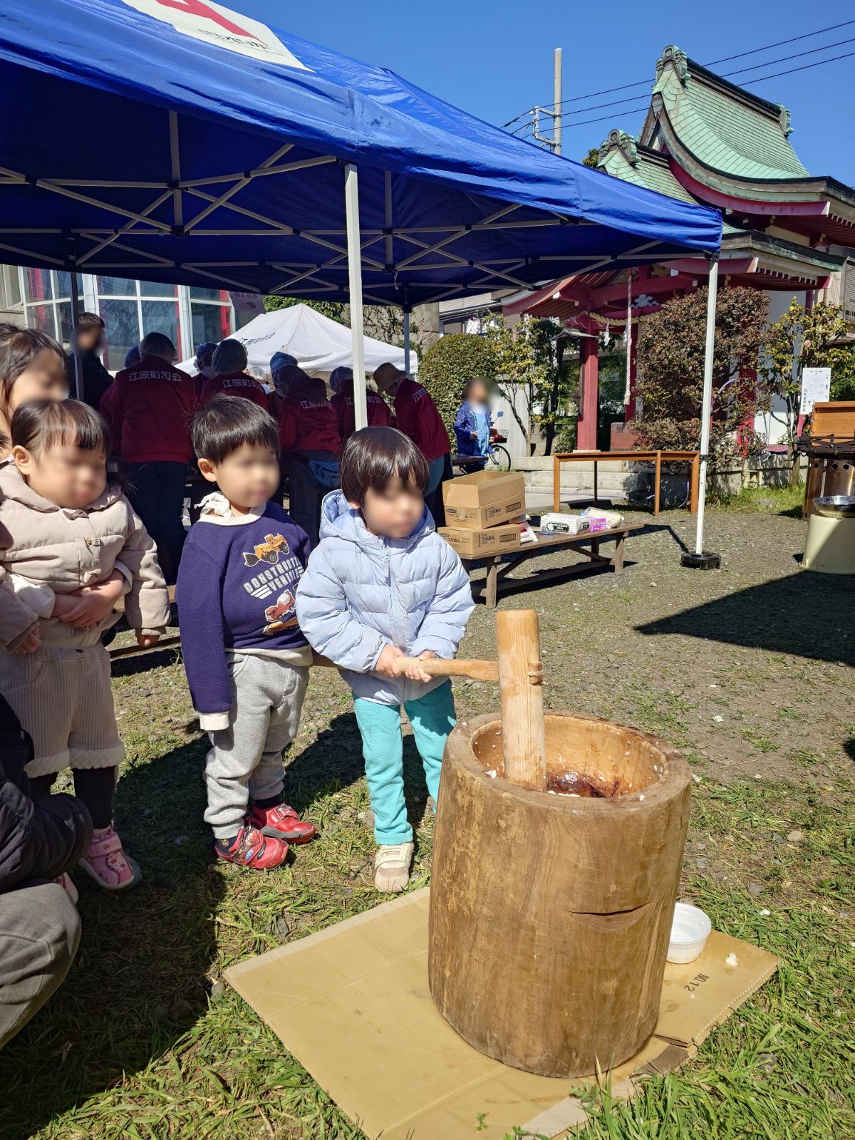 須賀稲荷神社の餅つき大会で、杵を持つ子どもと江原町町会の法被を着た役員